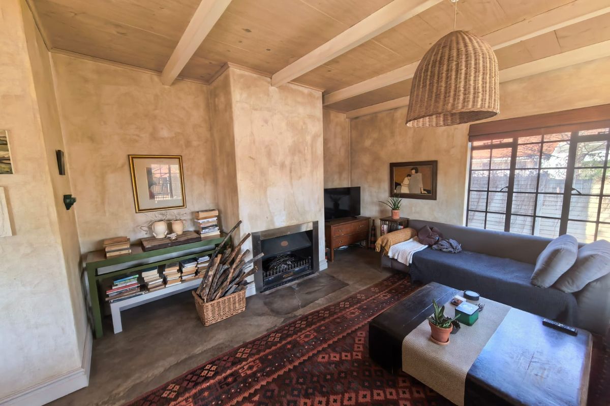 A cozy living room featuring a built-in fireplace, exposed beam ceiling, and concrete flooring, offering a rustic and character-filled atmosphere.