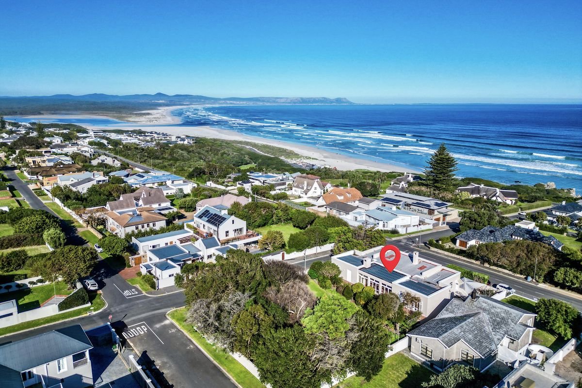 Aerial view of a coastal residential property featuring solar panels, situated in a prime location near the beach and ocean.