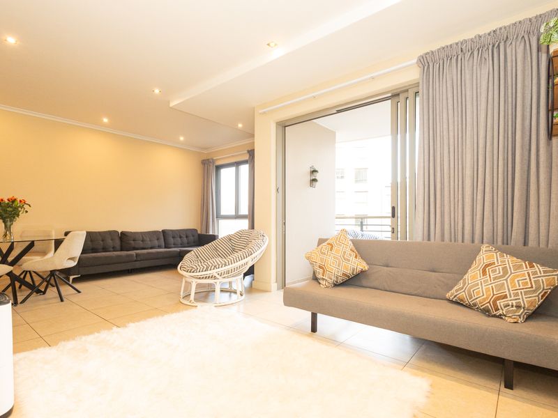 Spacious open-plan living and dining area featuring tiled floors, recessed lighting, and direct access to a private balcony through sliding glass doors.