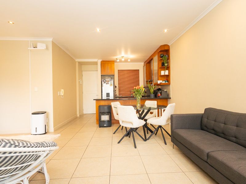 Open-plan living and dining area featuring tiled flooring, recessed lighting, and a functional kitchen with built-in cabinetry and a breakfast bar.