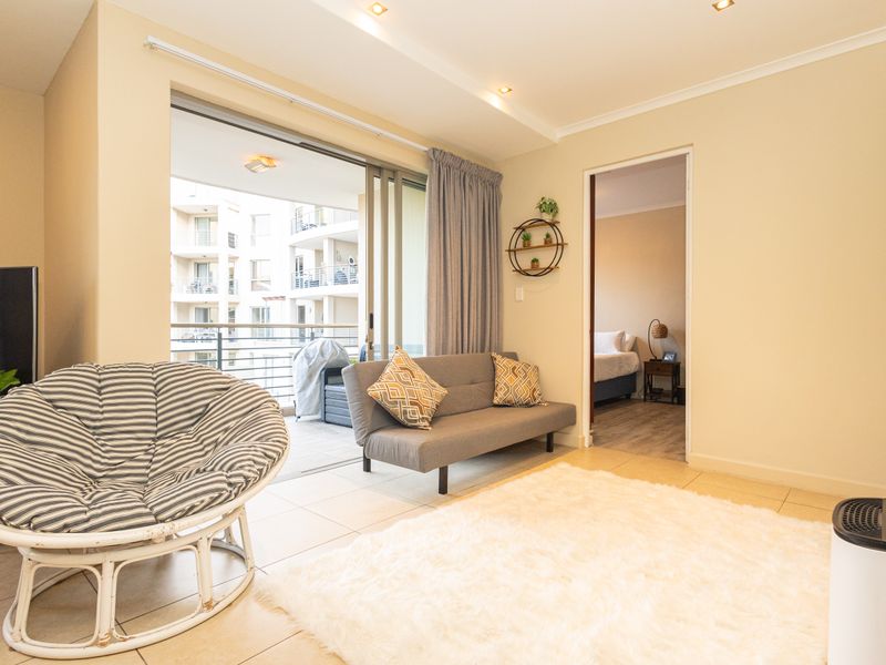 A bright living room featuring tiled flooring, recessed lighting, and a large sliding glass door providing access to a private balcony.