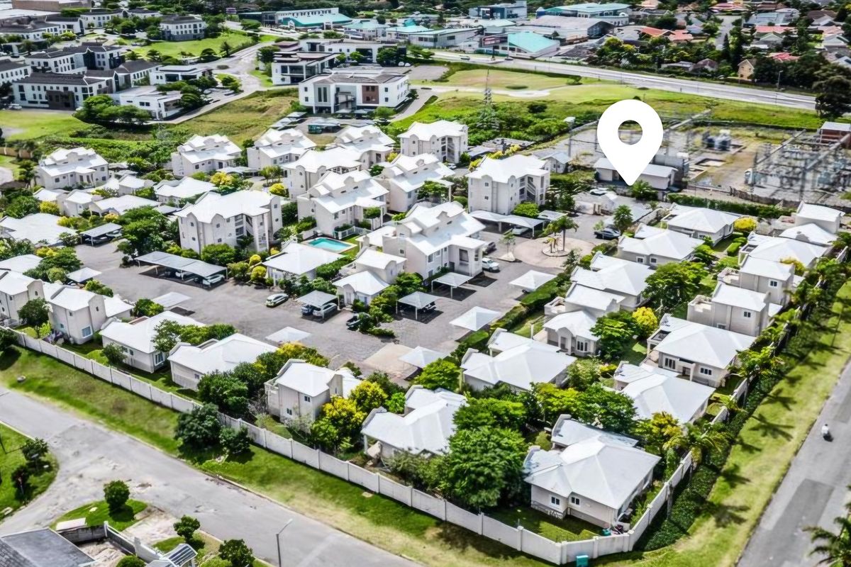 Aerial view of a residential apartment complex featuring multiple units, paved parking areas, carports, and a communal swimming pool.