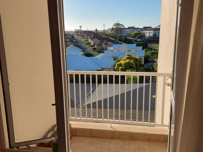 A private balcony featuring tiled flooring and a white metal balustrade, offering an elevated view over the surrounding residential neighborhood.