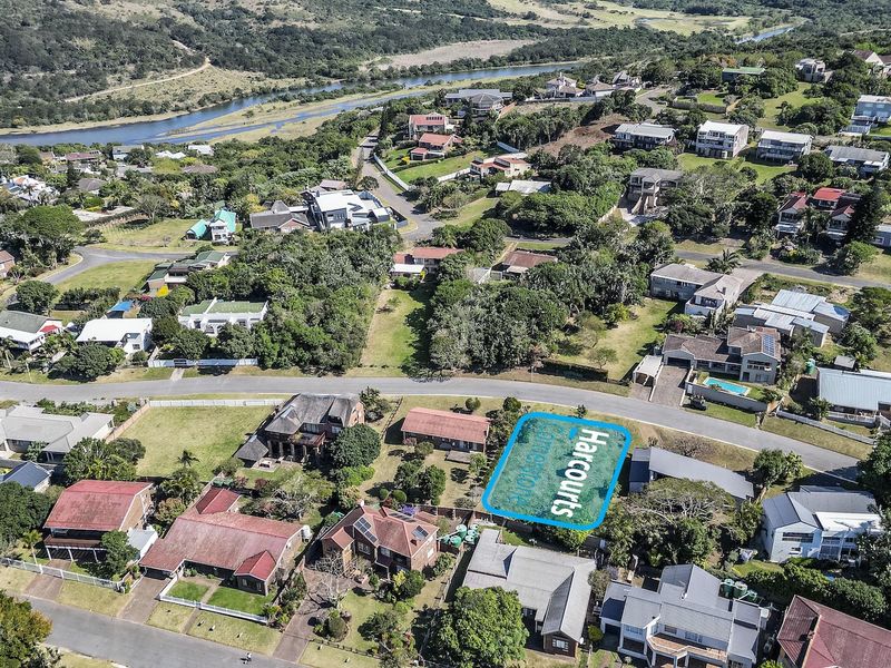 An aerial view of a vacant residential plot situated within an established coastal estate, offering proximity to local amenities and natural surroundings.