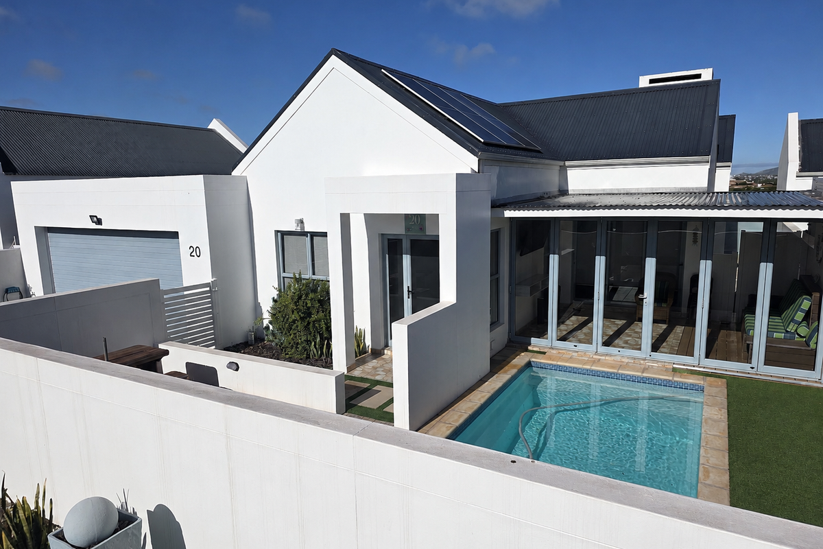 Modern rear exterior featuring a swimming pool, artificial lawn, and large sliding glass doors leading into the home, complemented by solar panels on the roof.
