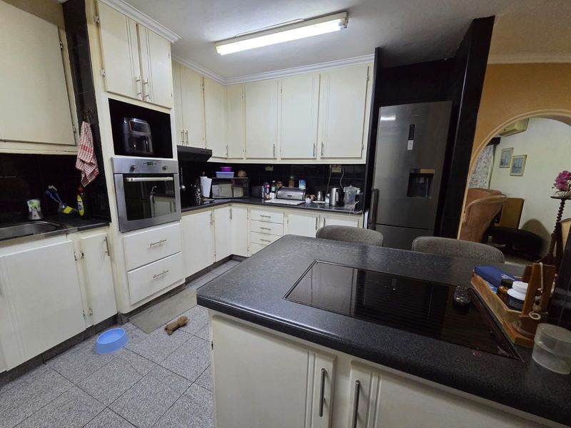 A functional kitchen featuring built-in cabinetry, a central island with a hob, and tiled flooring, offering a practical layout for daily cooking and preparation.