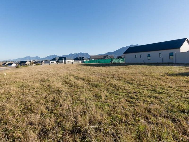 A vacant residential plot of land situated in a developed estate with mountain views and surrounding residential properties.