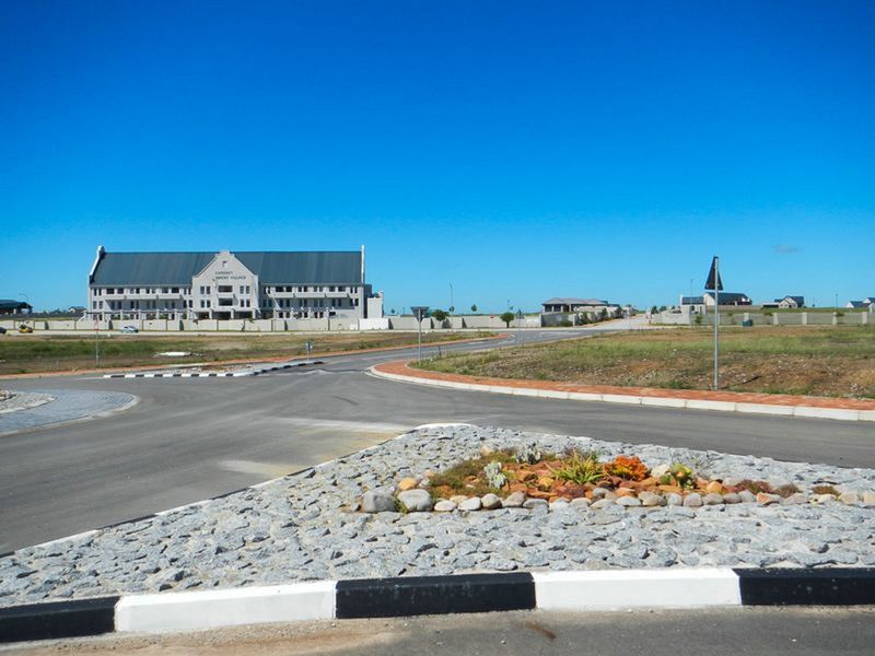 A view of the estate street infrastructure, featuring paved roads, concrete curbing, and a landscaped traffic island with stone mulch.