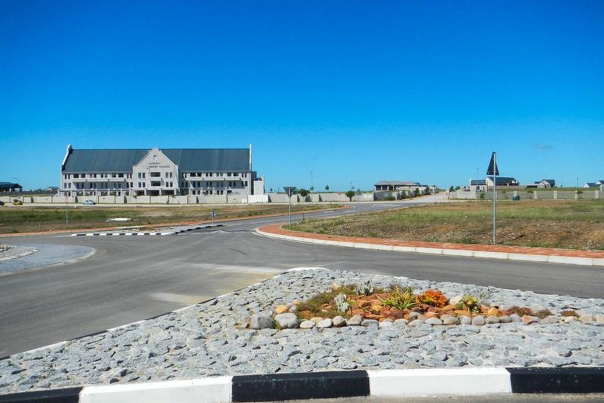 A view of the estate street infrastructure, featuring paved roads, concrete curbing, and a landscaped traffic island with stone mulch.