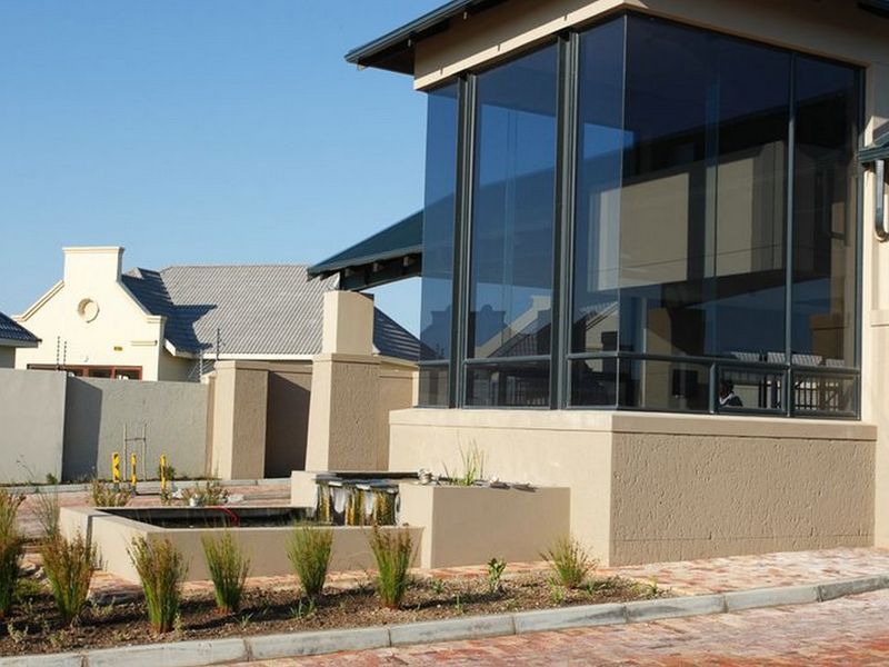 Modern architectural facade featuring extensive glass paneling, a built-in water feature, and paved driveway access.
