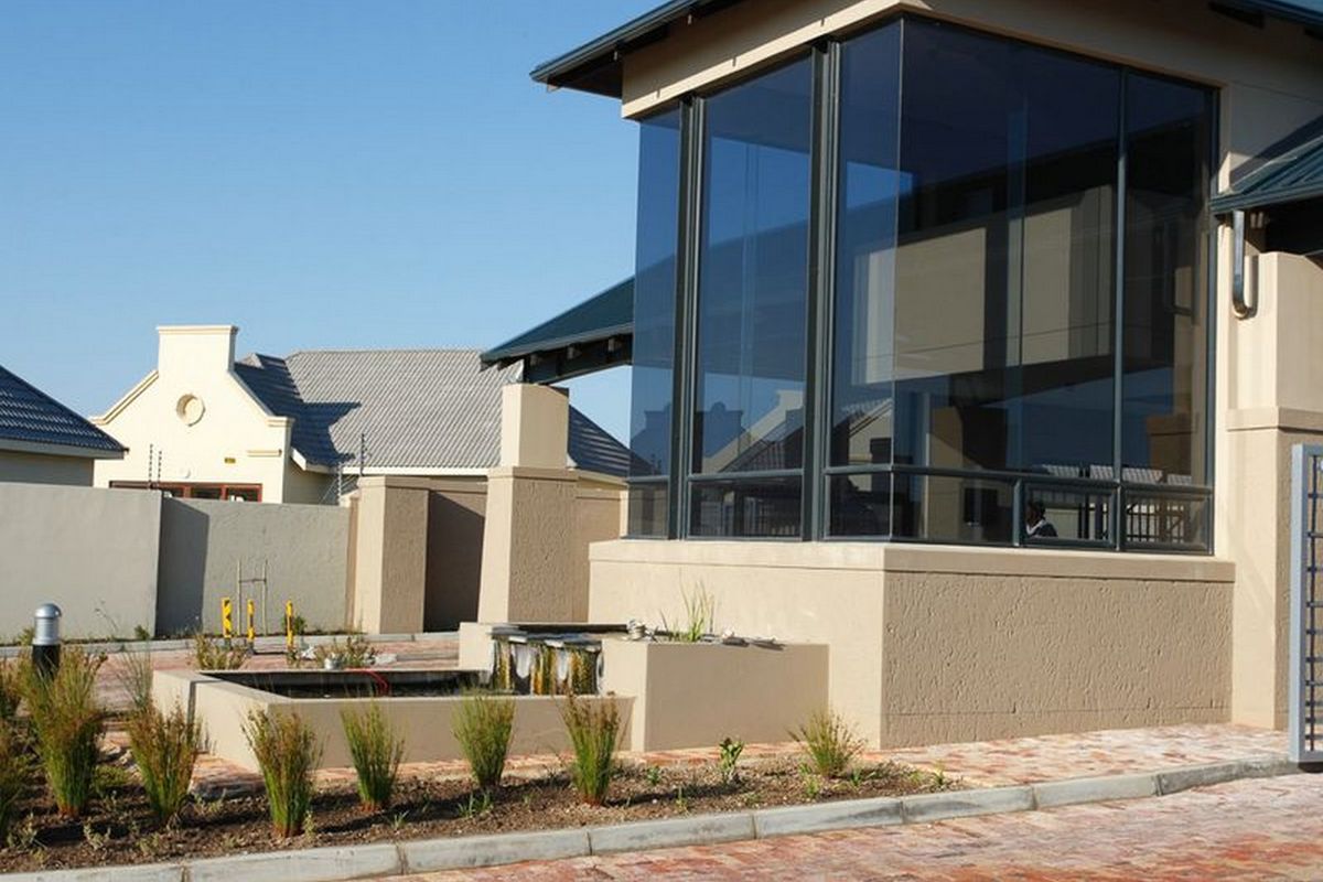 Modern architectural facade featuring extensive glass paneling, a built-in water feature, and paved driveway access.