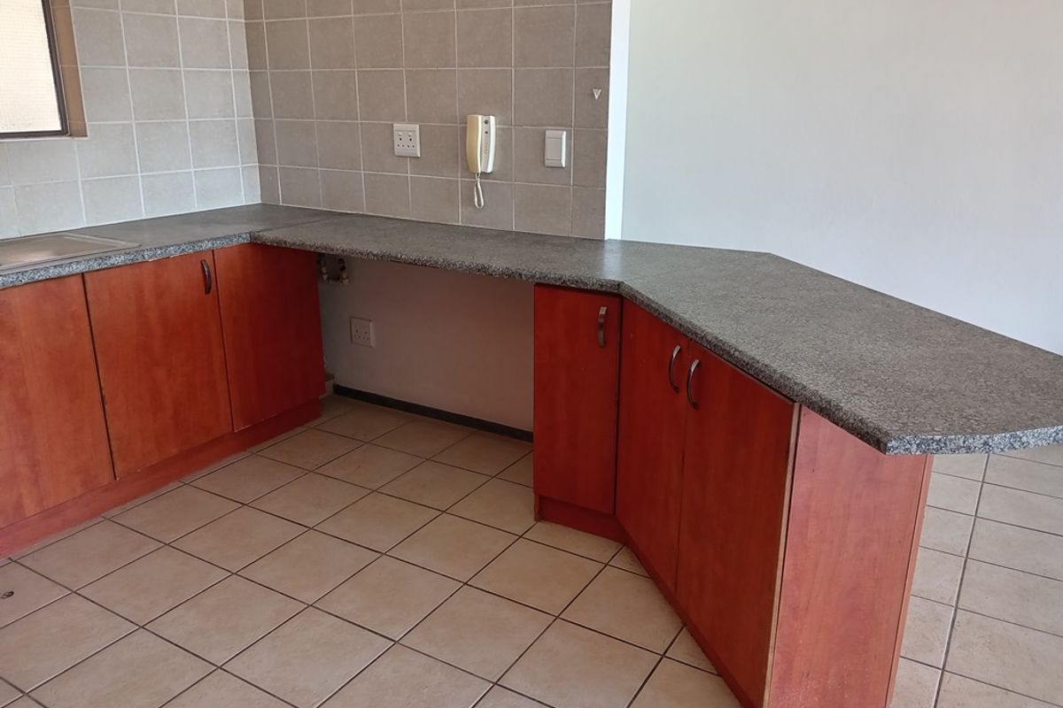 A functional kitchen area featuring laminate cabinetry, granite countertops, and tiled flooring, offering a clean and practical space ready for personalization.