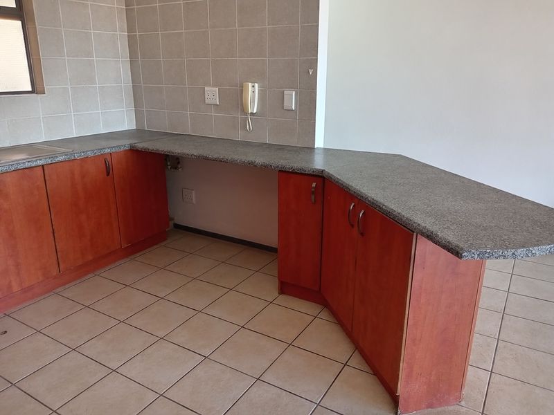A functional kitchen area featuring laminate cabinetry, granite countertops, and tiled flooring, offering a clean and practical space ready for personalization.