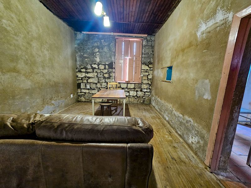 Rustic living area featuring exposed stone walls, timber ceiling, and original timber flooring, offering significant potential for renovation and restoration.