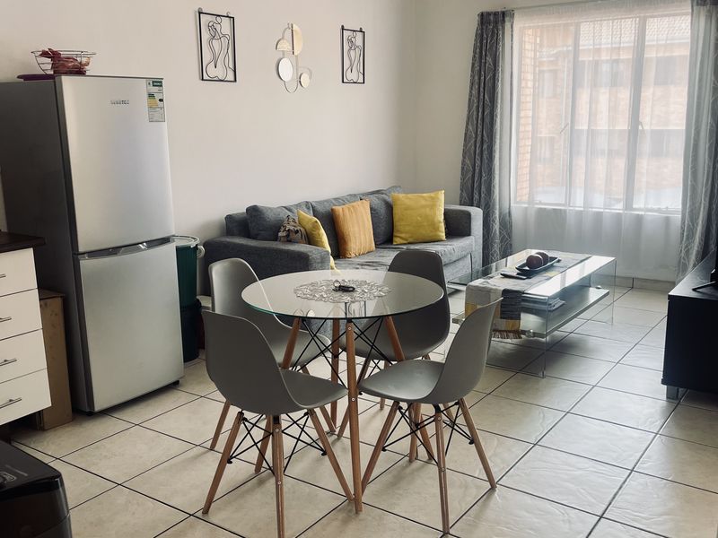 Open-plan living and dining area featuring tiled flooring and a compact kitchen layout, providing a functional and connected living space.