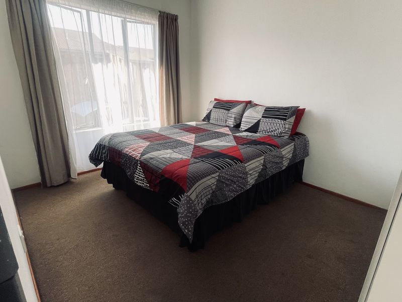 A standard bedroom featuring carpeted flooring and a large window with curtain tracks, providing natural light to the space.