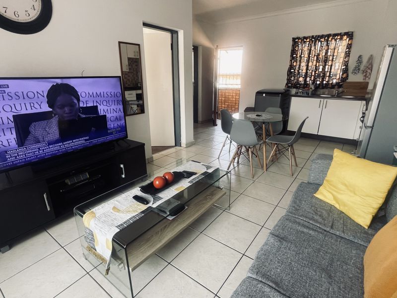 Open plan living area featuring tiled flooring and a compact kitchen corner with built-in cabinetry and sink.