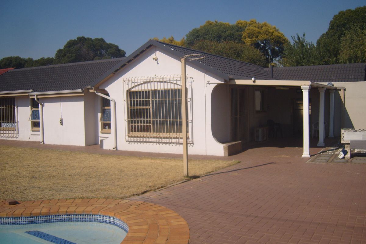 Rear view of the house featuring a tiled roof, covered patio area, and a swimming pool with brick paving.