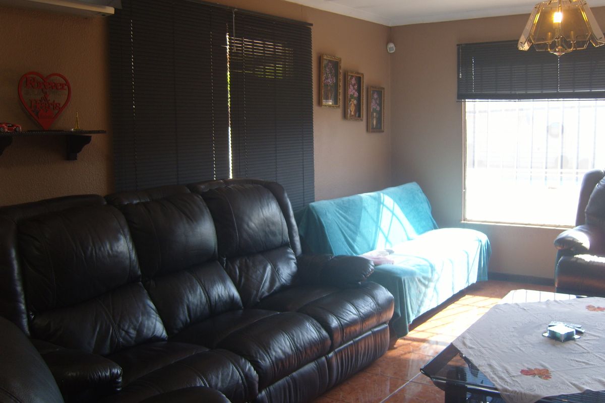 A living room featuring tiled flooring, venetian blinds, and an installed air conditioning unit, providing a functional and comfortable living space.