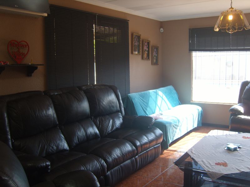 A living room featuring tiled flooring, venetian blinds, and an installed air conditioning unit, providing a functional and comfortable living space.