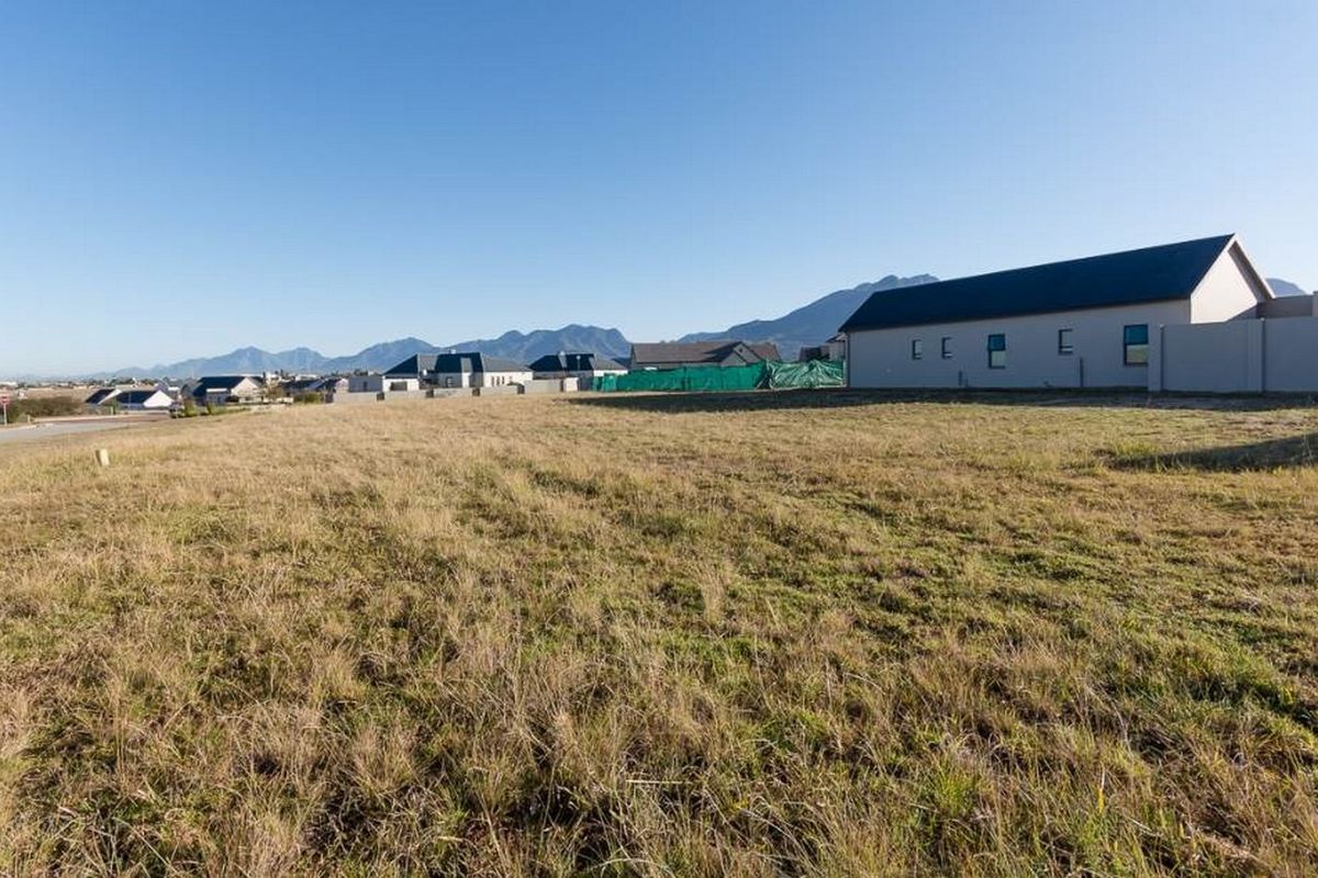 A vacant residential plot of land situated in a developed estate with mountain views and surrounding residential properties.