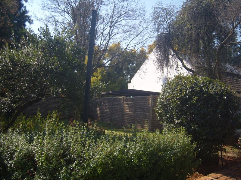 A view of the property's garden area featuring mature trees and a brick boundary wall.