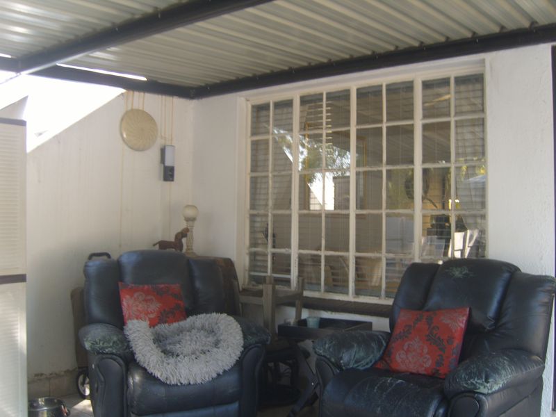 A covered patio area featuring a corrugated metal roof and a large multi-pane steel window, providing a sheltered outdoor space.