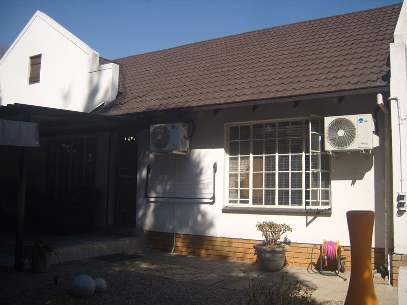 Rear exterior view of the townhouse featuring a tiled roof, paved patio area, and wall-mounted air conditioning units.