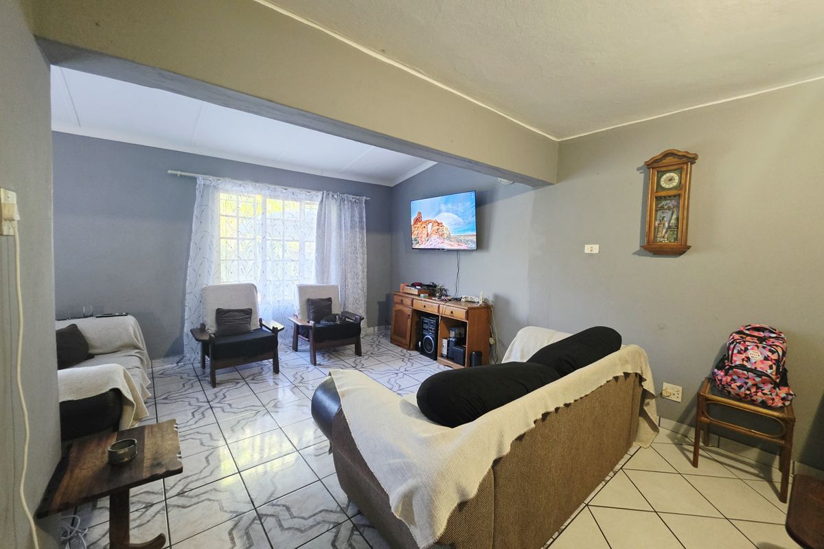 A living room area featuring tiled flooring and coved ceilings, currently presented with a neutral wall color scheme.