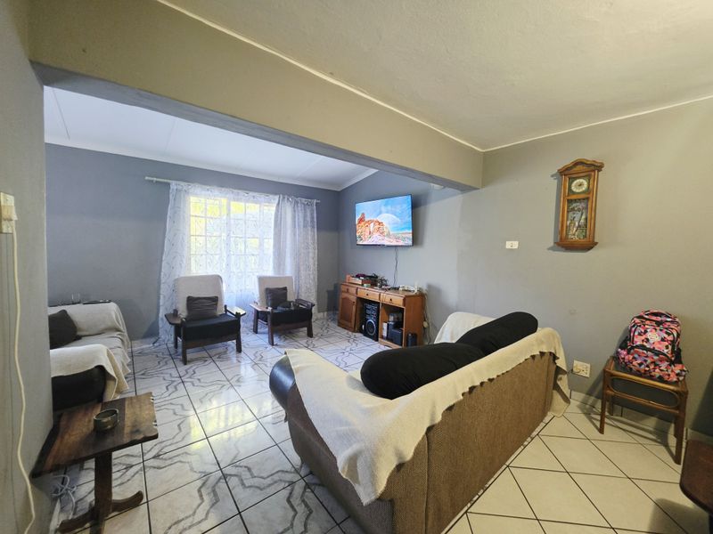 A living room area featuring tiled flooring and coved ceilings, currently presented with a neutral wall color scheme.