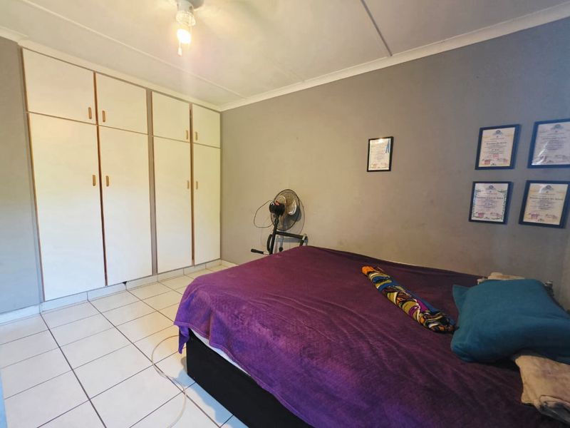 A functional bedroom featuring tiled flooring and built-in cupboards, offering practical storage space within the apartment.