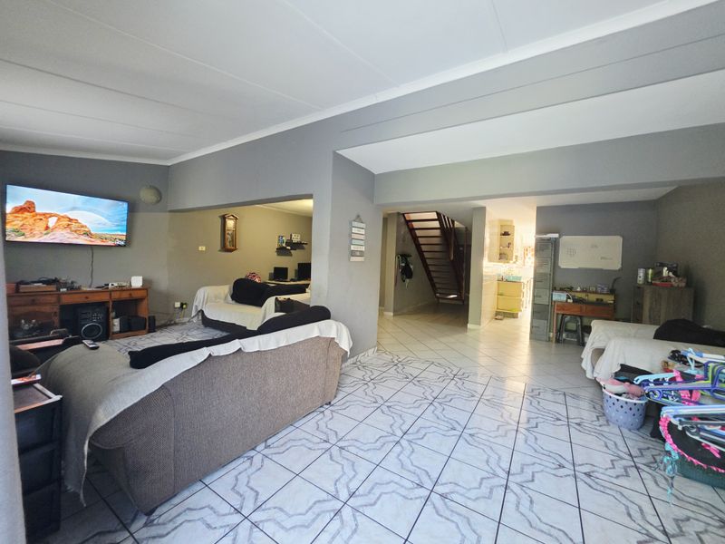Spacious open-plan living area featuring tiled flooring and a central staircase leading to the upper level, offering a versatile layout for family living.
