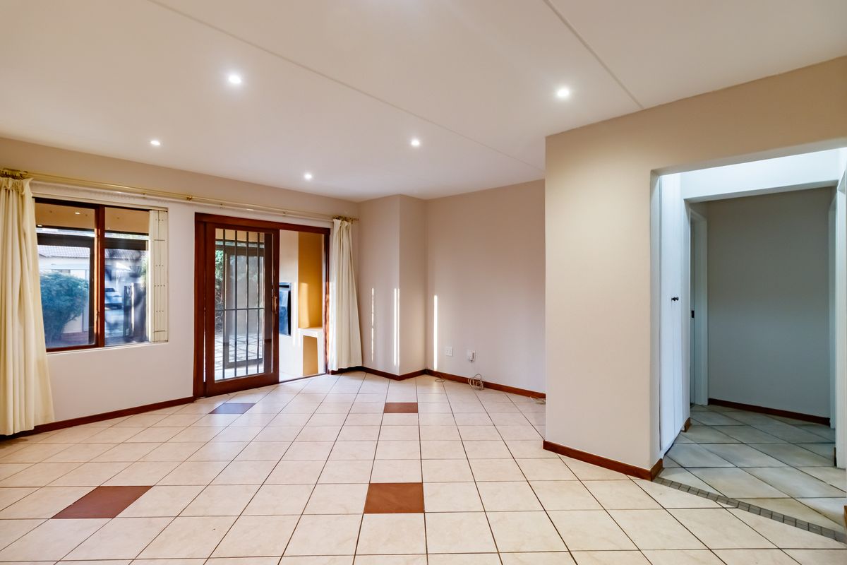 Spacious, light-filled living area featuring neutral ceramic floor tiles, recessed downlighting, and direct access to an outdoor patio through a sliding glass door.