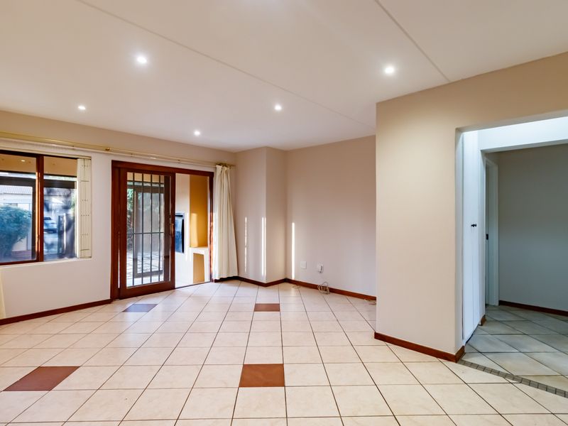 Spacious, light-filled living area featuring neutral ceramic floor tiles, recessed downlighting, and direct access to an outdoor patio through a sliding glass door.