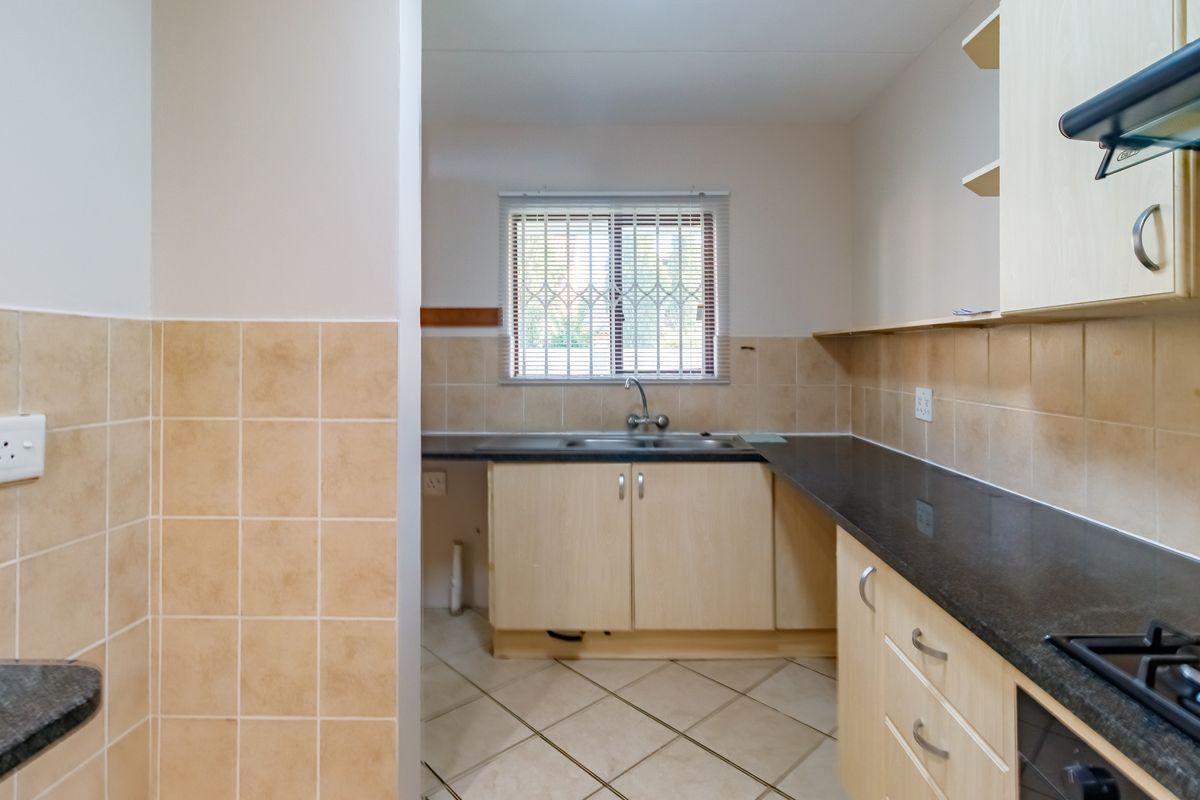 A functional kitchen featuring laminate cabinetry, granite countertops, ceramic tile backsplash, and tiled flooring, currently vacant and ready for updates.