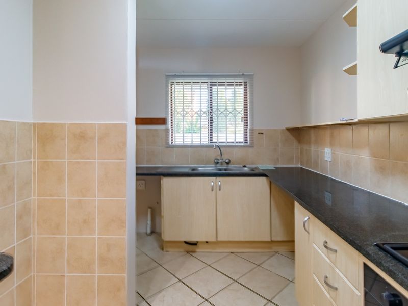 A functional kitchen featuring laminate cabinetry, granite countertops, ceramic tile backsplash, and tiled flooring, currently vacant and ready for updates.