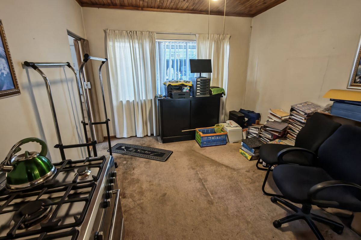 Kitchen area featuring a gas stove and timber ceiling, currently used as a multi-purpose workspace with worn carpeting.