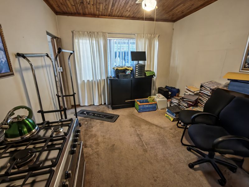 Kitchen area featuring a gas stove and timber ceiling, currently used as a multi-purpose workspace with worn carpeting.