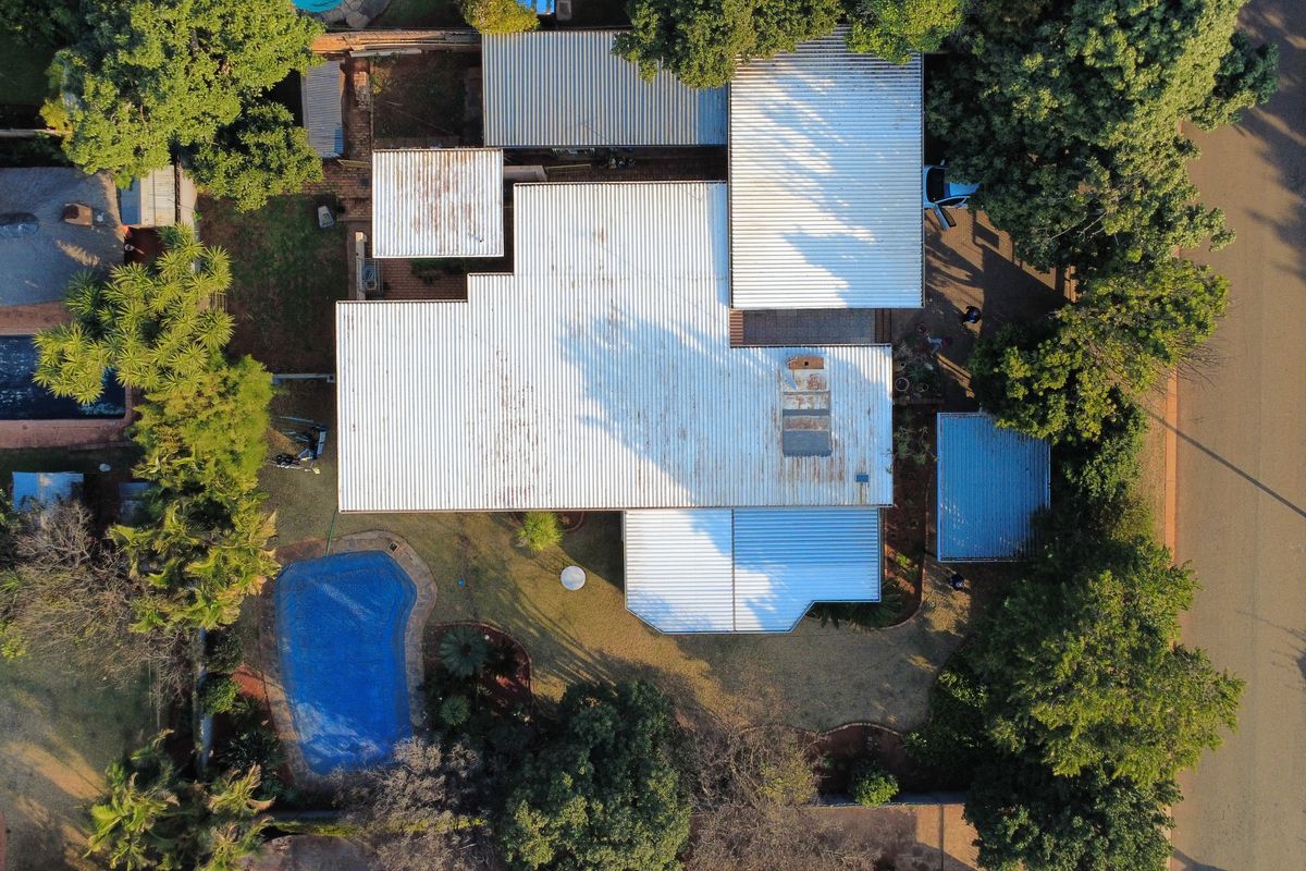 Aerial view of the property showcasing the roof structure, swimming pool, and surrounding garden area.