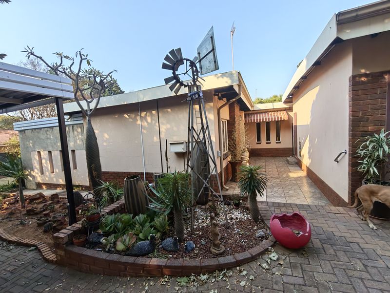 A rear courtyard area featuring brick paving, a raised garden bed, and a decorative windmill structure against the house exterior.