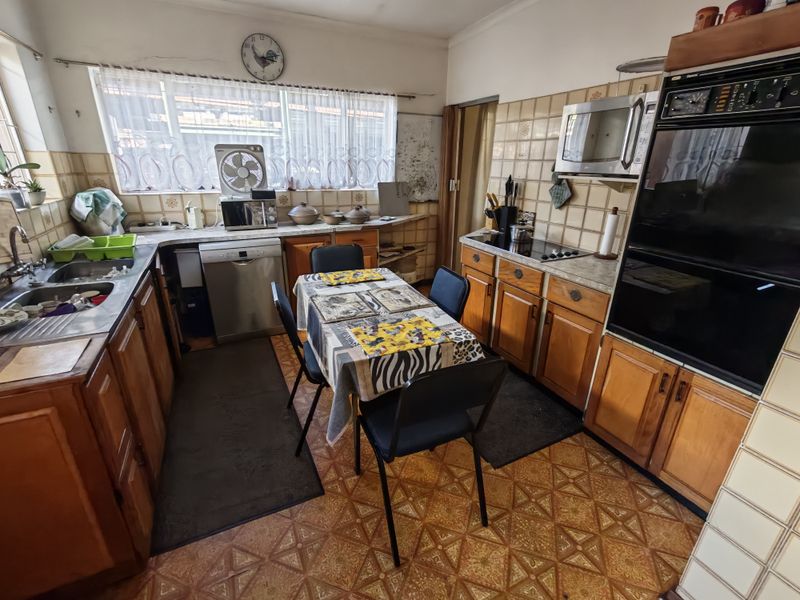 A dated kitchen featuring wooden cabinetry, built-in appliances, tiled backsplash, and patterned flooring, offering significant potential for a modern renovation.