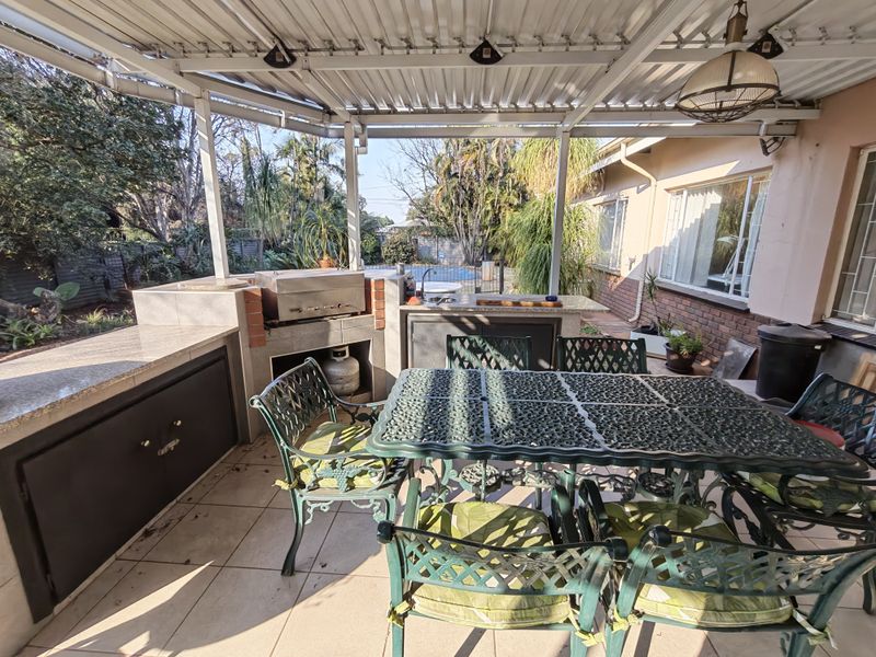 Covered outdoor patio featuring a built-in braai, granite prep surfaces, and a sink, ideal for alfresco dining and entertaining.