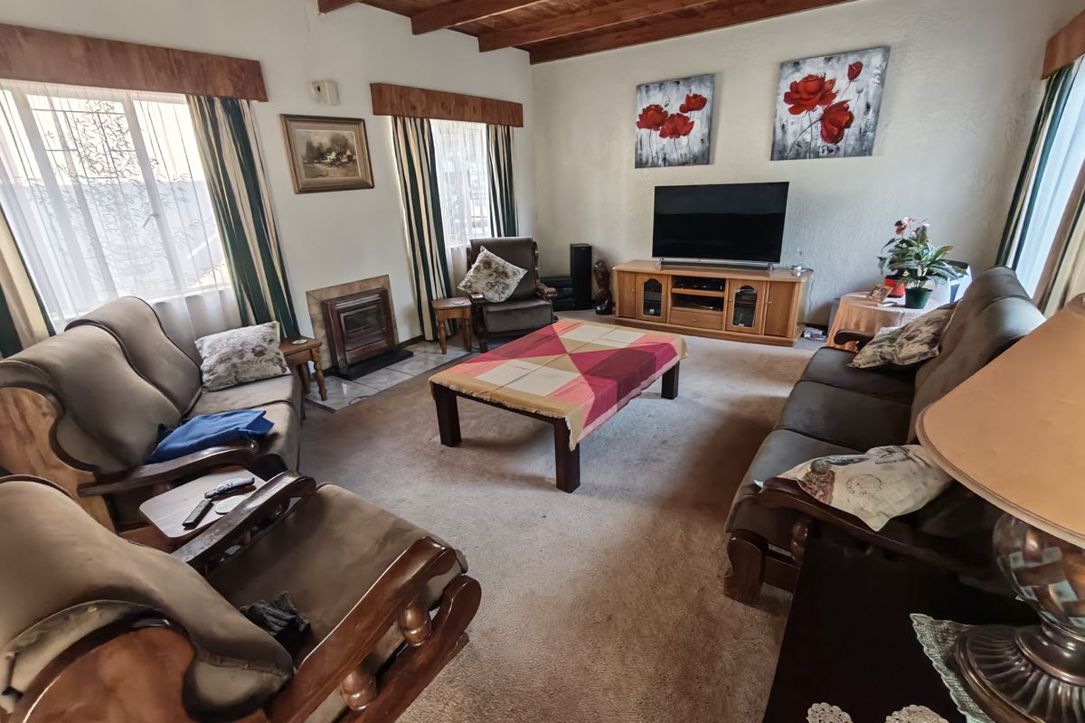 A cozy living room featuring exposed timber ceiling beams and a built-in fireplace with a tiled hearth.