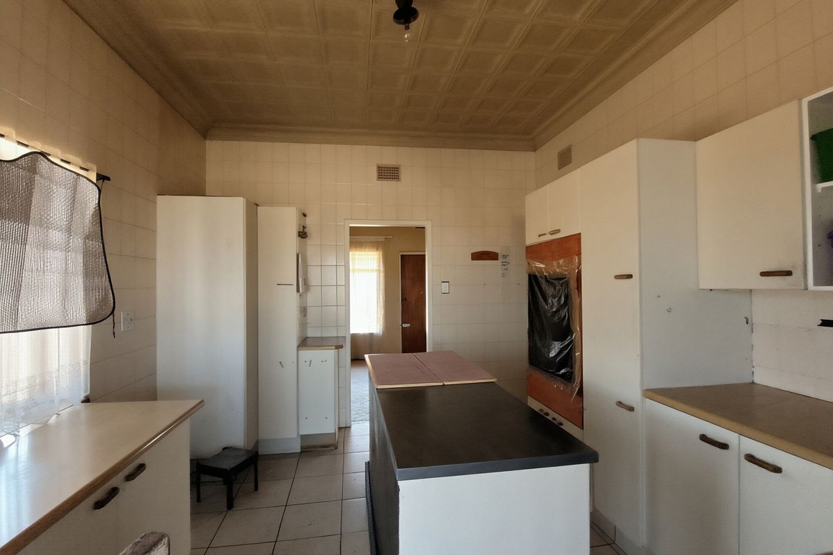 A dated kitchen featuring tiled walls, built-in cabinetry, and a central island, offering a blank canvas for a modern renovation.