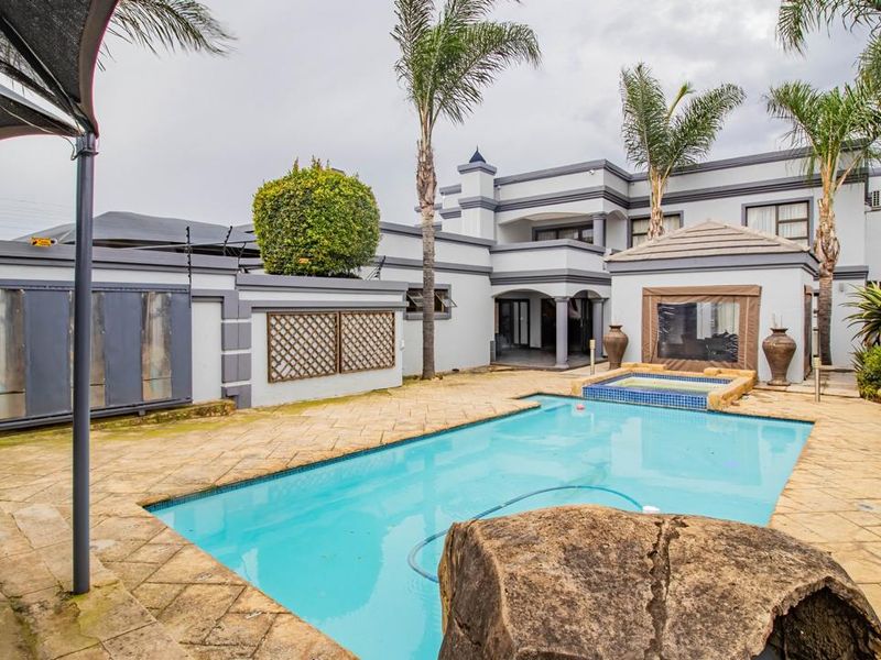 Spacious rear garden area featuring a swimming pool with an integrated raised spa, paved surround, and perimeter walling with electric fencing.