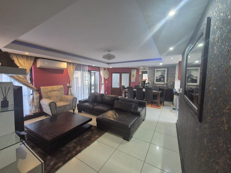 Spacious open-plan living and dining area featuring tiled floors, recessed lighting, a stone feature wall, and direct access to the outdoor space.