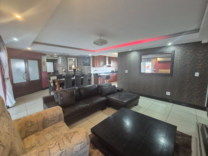 Spacious open-plan living and dining area featuring tiled floors, recessed lighting, and a modern kitchen with built-in cabinetry and stone feature wall accents.