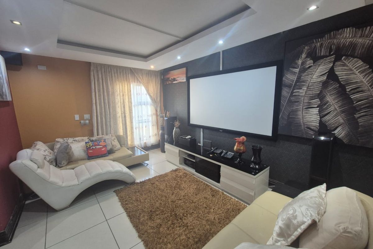 A comfortable living room featuring tiled flooring, recessed ceiling lighting, and a dedicated media wall setup.