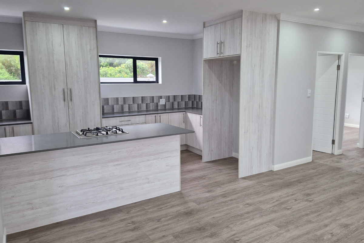Modern kitchen featuring light wood-grain cabinetry, stone countertops, a built-in gas hob, and neutral tiled backsplash, presented in a clean, open-plan layout.