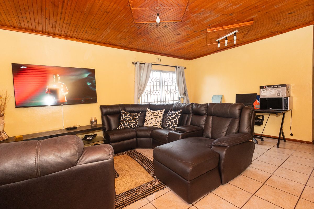 A living room featuring ceramic floor tiles and a timber tongue and groove ceiling, providing a functional space with potential for modern updates.